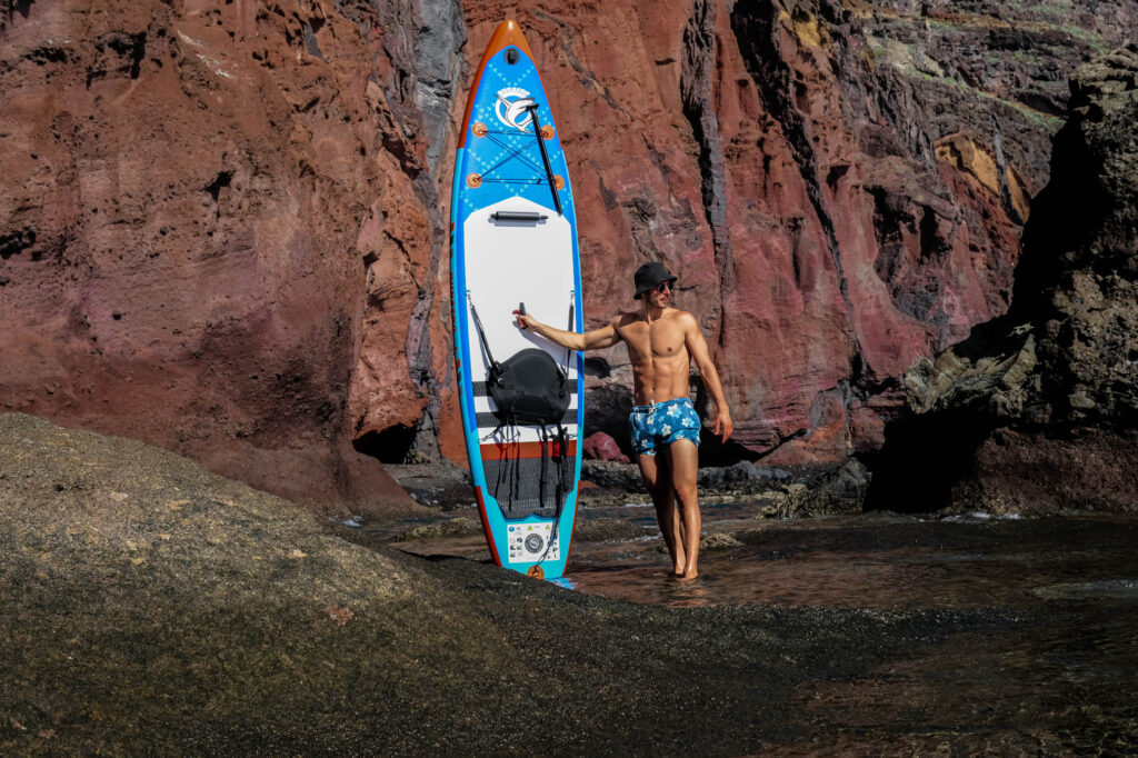 Young men arriving to an impressive location with his paddleboard in Tenerife