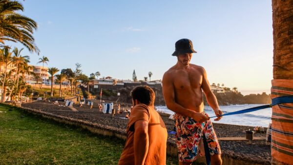 Setting up a slackline between palm trees at sunset in Tenerife – outdoor adventure preparation